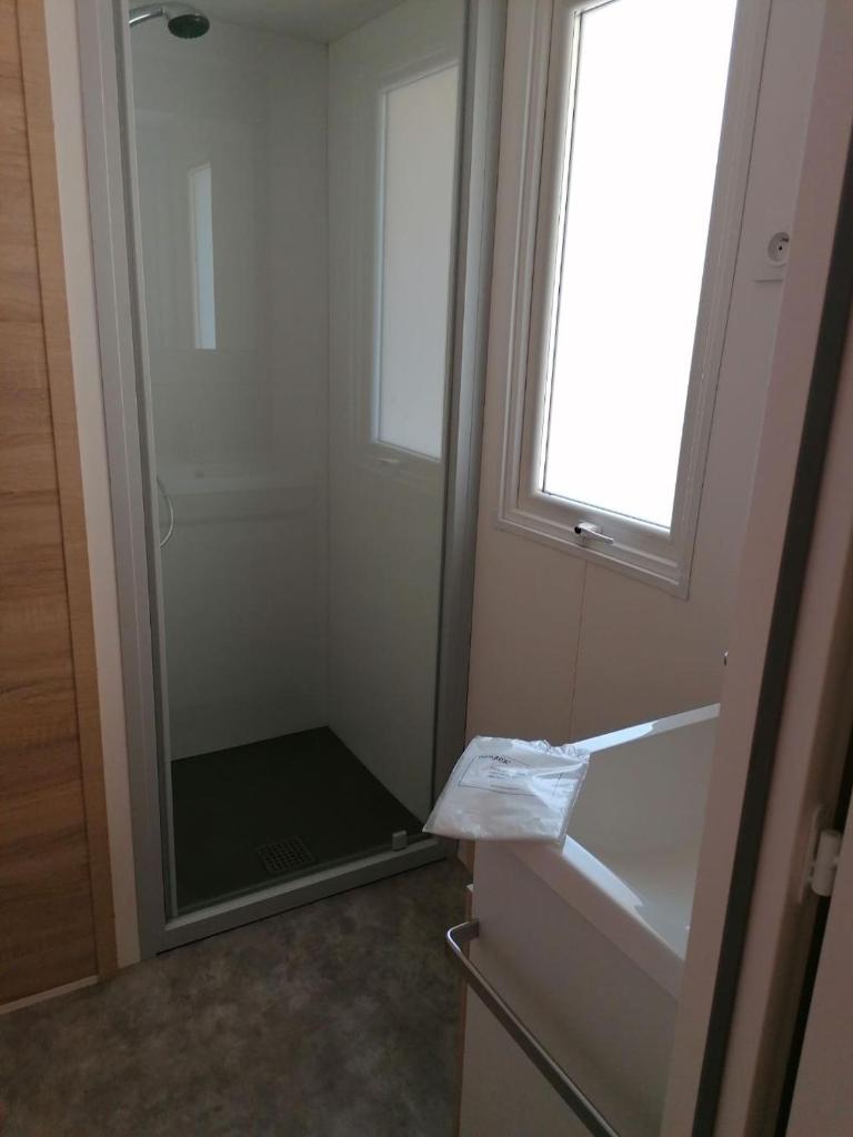 d'une douche avec une porte en verre et une fenêtre. dans l'établissement MOBIL-HOME NEUF 6 PERSONNES réservation du samedi au samedi en juillet et août, à Urt