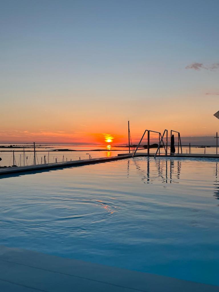 une piscine avec le coucher de soleil en arrière-plan dans l'établissement Laguna Faro Suites - Adults Only, à Grado