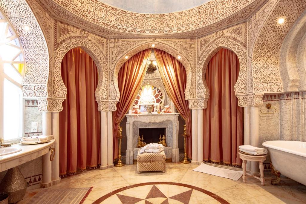 La salle de bains est pourvue d'un rideau rouge, d'une baignoire et d'une cheminée. dans l'établissement Riad Dar El Malaika, à El Jadida