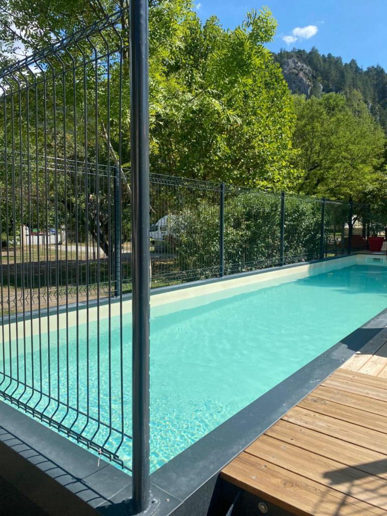 une piscine entourée d'une clôture dans l'établissement Camping Frédéric Mistral, à Castellane