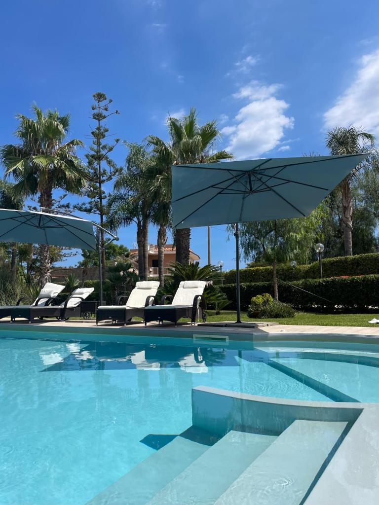 une piscine avec des chaises et un parasol dans l'établissement Villa mare Fontane Bianche, à Fontane Bianche
