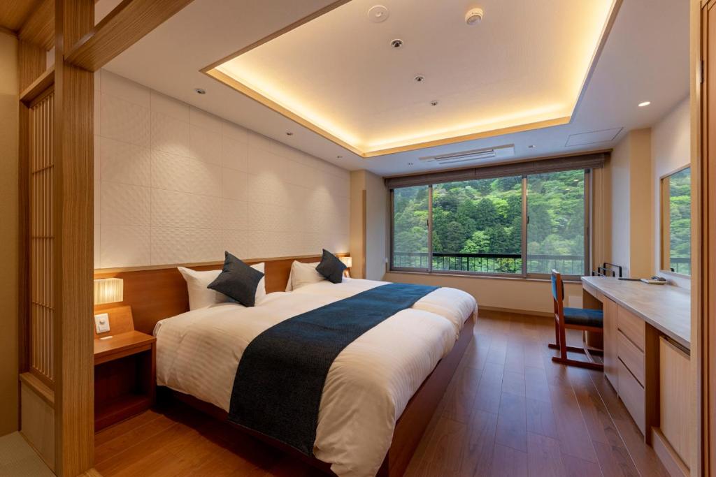 une chambre avec un grand lit et une grande fenêtre dans l'établissement Shikanoyu Hotel, à Komono 37 autres photos