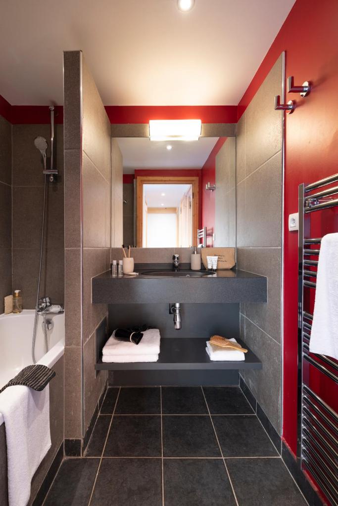 une salle de bain avec un lavabo, une baignoire et un miroir dans l'établissement Résidence Pierre & Vacances Premium les Crets, à Les Allues 37 autres photos