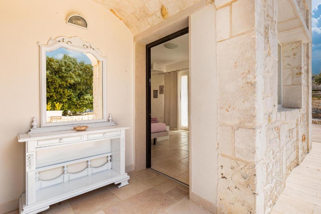 La salle de bains est pourvue d'un miroir et d'une commode blanche. dans l'établissement Casa Marangi by BarbarHouse, à Ostuni