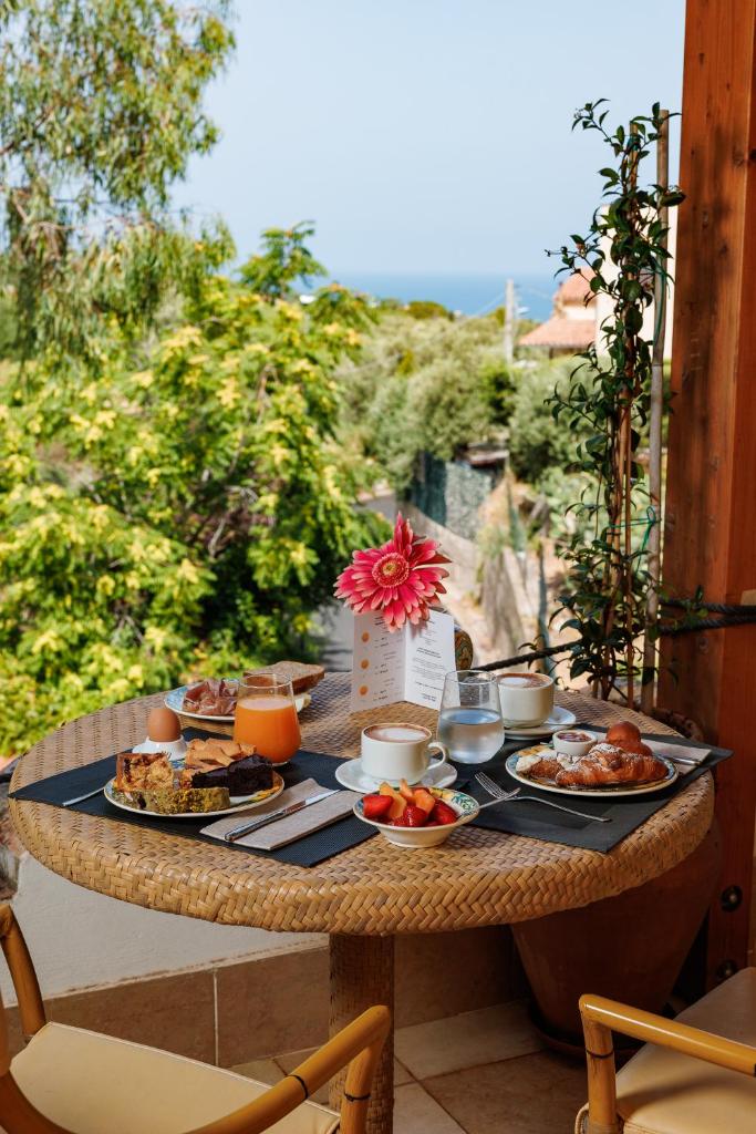 une table avec des assiettes de nourriture sur une terrasse dans l'établissement Alberi del Paradiso, à Cefalù