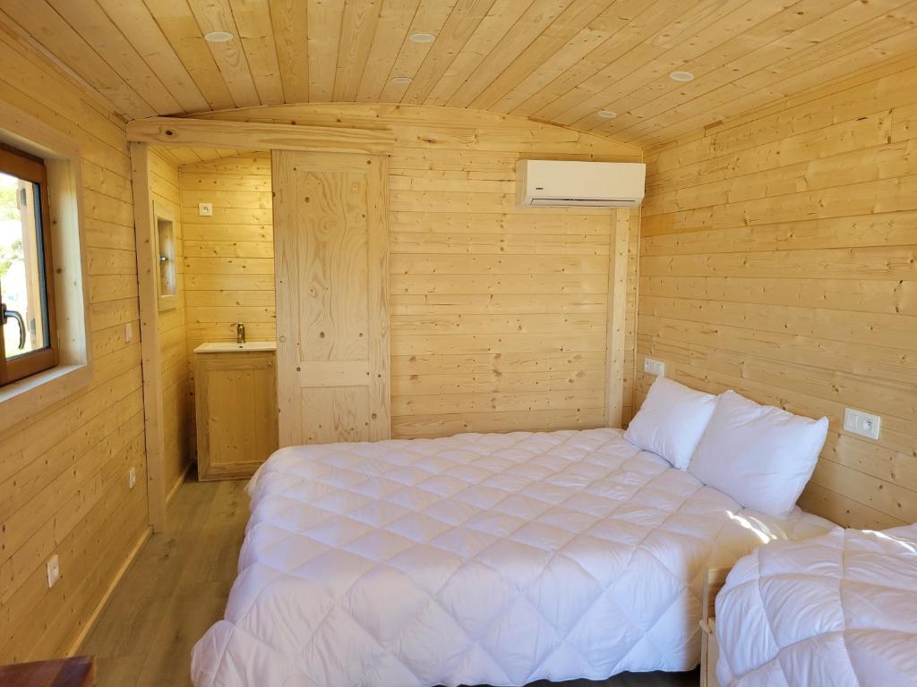 Cette chambre en bois comprend un lit blanc. dans l'établissement Roulotte à Sapharey, à Sarrazac 16 autres photos