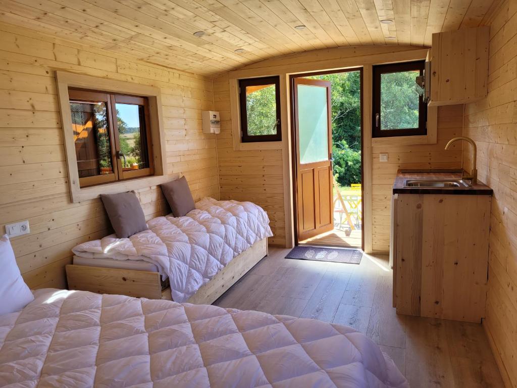 - une chambre dans une cabane en rondins avec un lit et un lavabo dans l'établissement Roulotte à Sapharey, à Sarrazac
