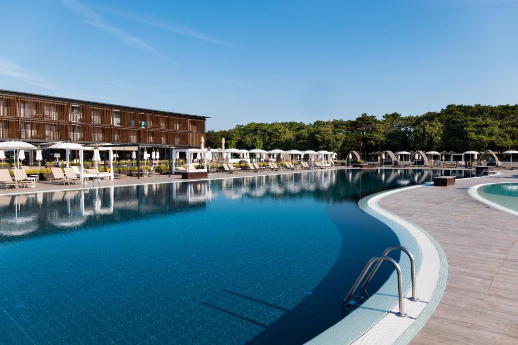 une grande piscine avec des chaises et un hôtel dans l'établissement Lino delle Fate Eco Resort, à Bibione