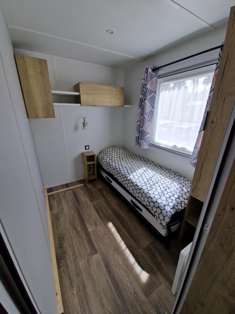 une petite pièce avec un lit et une fenêtre dans l'établissement spacieux mobil-home 3 ch, à Saint-Jean-de-Monts