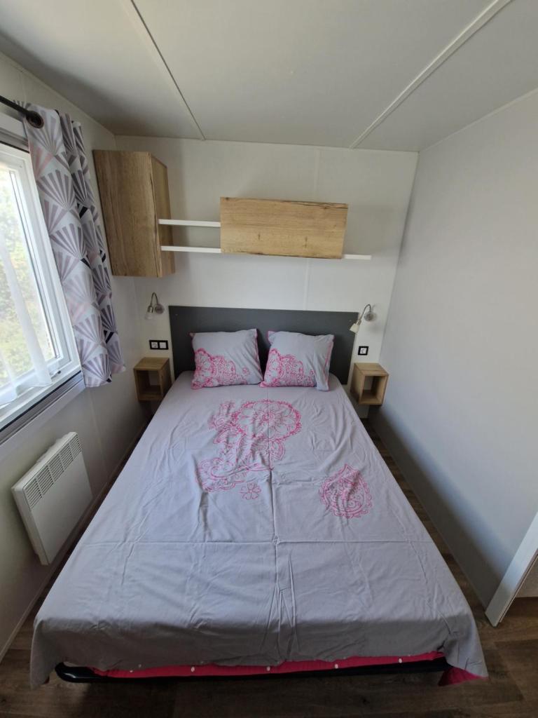 une chambre avec un grand lit avec des oreillers roses dans l'établissement spacieux mobil-home 3 ch, à Saint-Jean-de-Monts 20 autres photos