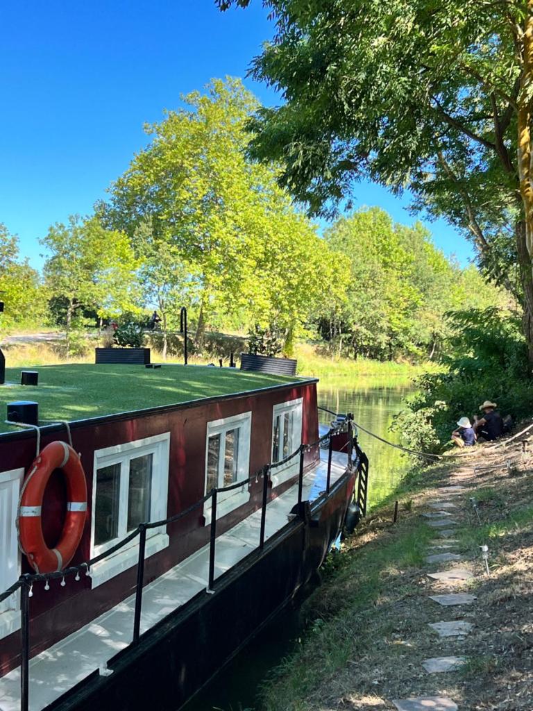 un bateau garé sur le côté d'un canal dans l'établissement Péniche Dondon - Gîte cocooning sur Canal du midi, à Avignonet-de-Lauragais 17 autres photos
