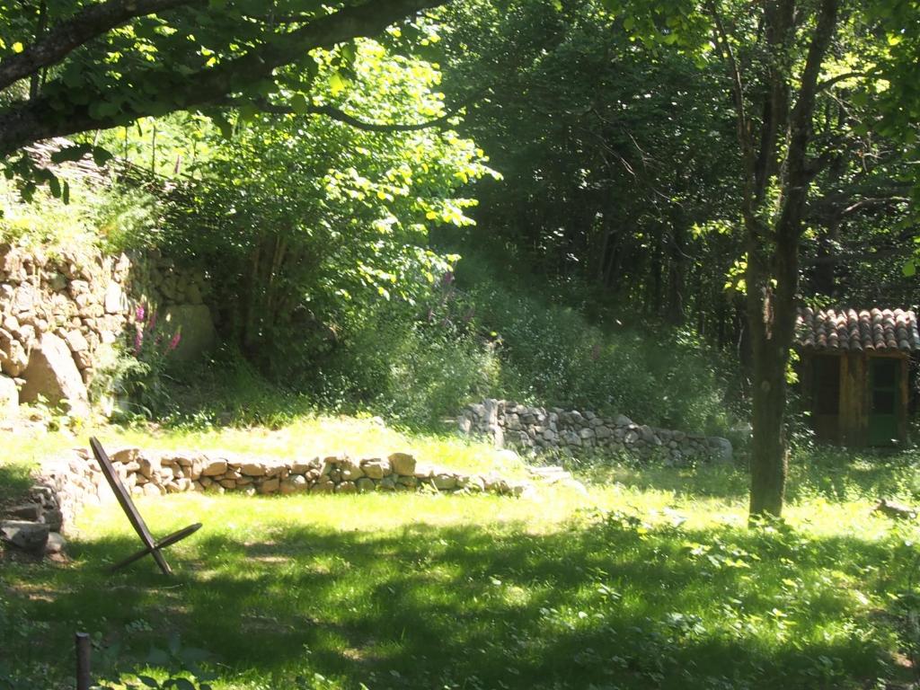 un jardin avec un mur en pierre dans la pelouse dans l'établissement Grande Tente Tipi en pleine forêt, à Burzet