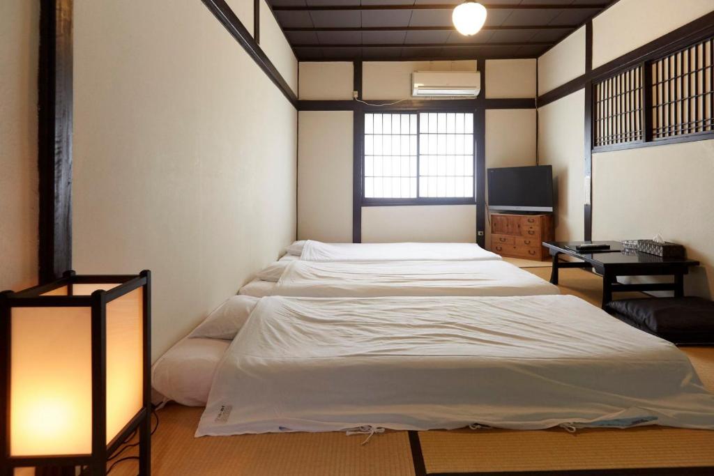 une chambre avec un grand lit et un bureau dans l'établissement Takeyaso Ryokan, à Amagasaki