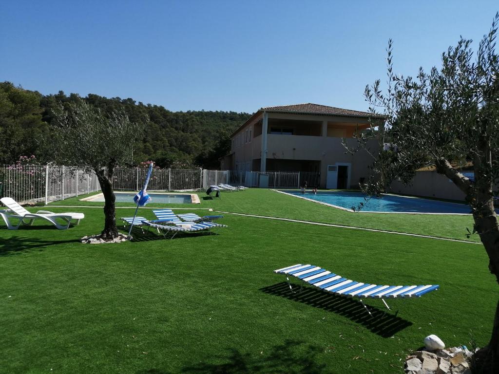 une cour avec des chaises longues et une piscine dans l'établissement Charmant mobil-home, à Rocbaron