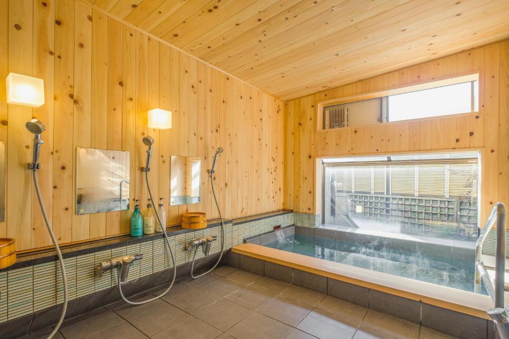 La grande salle de bains est pourvue d'une baignoire et d'une fenêtre. dans l'établissement Hamabe no Yado Asahiya, à Himi