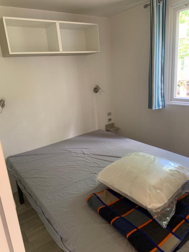 un lit dans une chambre blanche avec une fenêtre dans l'établissement Mobil home 6 personnes camping 4* Mimizan, à Aureilhan