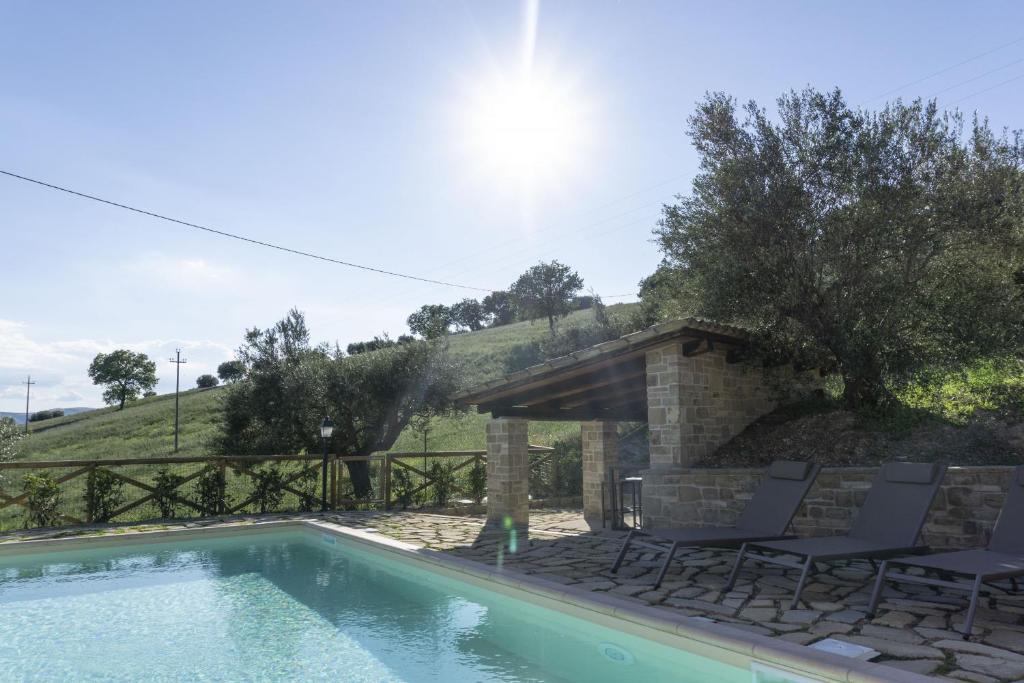 - une piscine avec des chaises à côté d'une maison dans l'établissement Villa alla Torre - Homelike Villas, à San Severino Marche