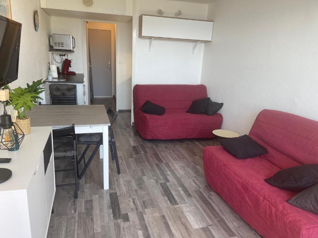 un salon avec un canapé rouge et une table dans l'établissement Studio au pied des pistes 4 pers, Alpes Le Corbier, au Corbier