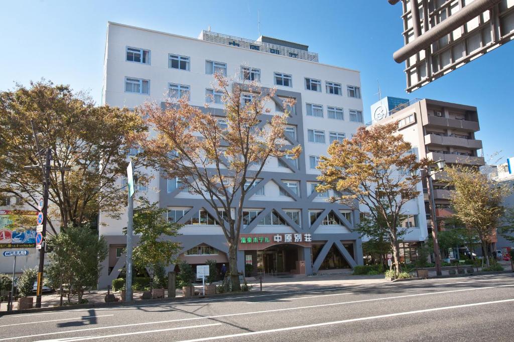 un bâtiment blanc avec des arbres en face d'une rue dans l'établissement Onsen Hotel Nakahara Bessou Nonsmoking, Earthquake retrofit, à Kagoshima