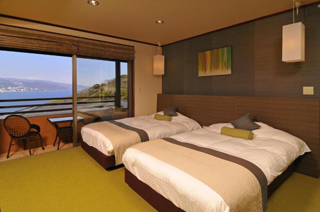 une chambre d'hôtel avec deux lits et un balcon dans l'établissement Uminohana, à Atami