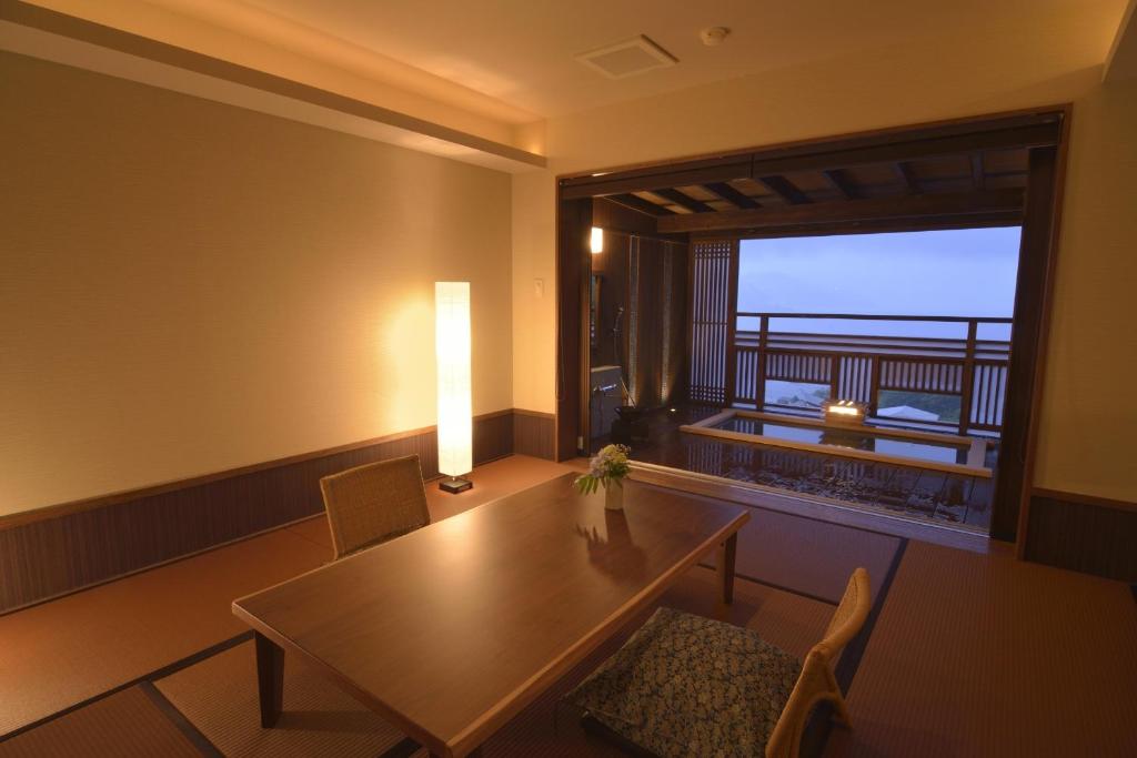 une salle à manger avec une table et une grande fenêtre dans l'établissement Uminohana, à Atami