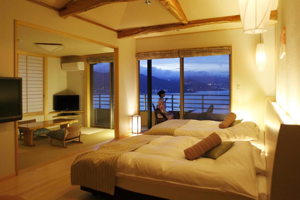 une chambre d'hôtel avec deux lits et une grande fenêtre dans l'établissement Uminohana, à Atami