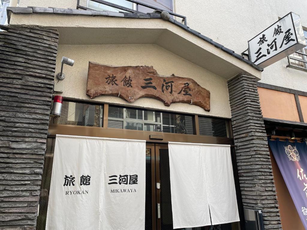 un bâtiment avec une enseigne sur le côté dans l'établissement Ryokan Mikawaya, à Tokyo