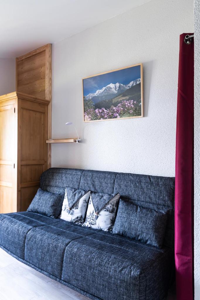 un canapé bleu avec des coussins dans un salon dans l'établissement Le Gypaète, à Morillon