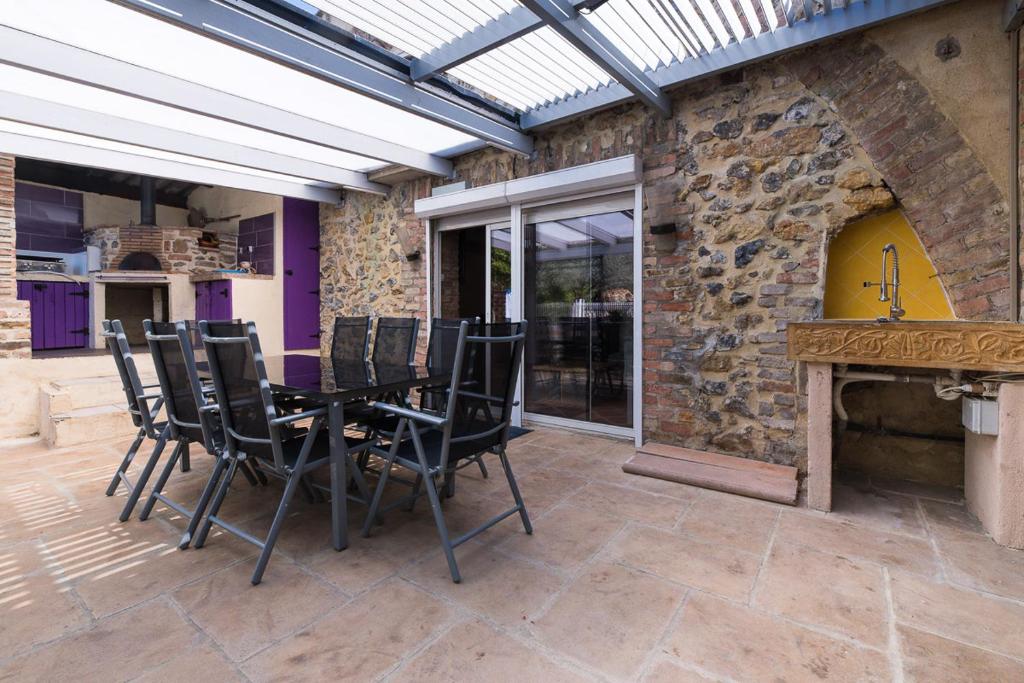 un patio avec une table et des chaises et un mur en pierre dans l'établissement Gîte cévenol avec SPA et Piscine privatifs, à Saint-Martin-de-Valgalgues