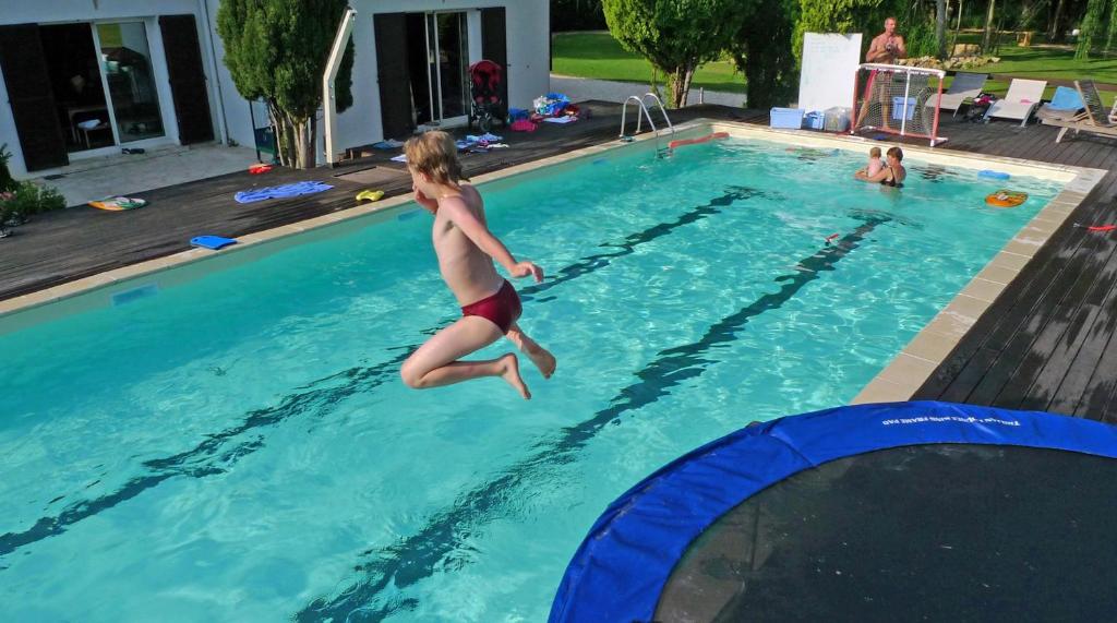un jeune garçon sautant dans une piscine dans l'établissement Les Bulles de la Maison du Rocher, à Noisy-sur-École