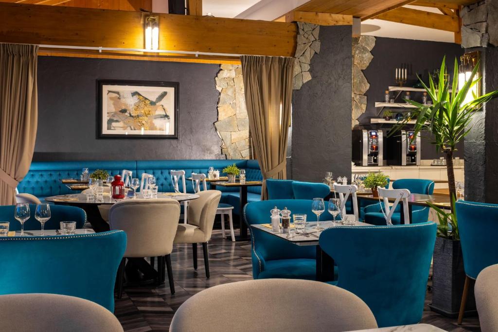 un restaurant avec des tables et des chaises bleues dans l'établissement Hôtel Aalborg, à Les Deux Alpes