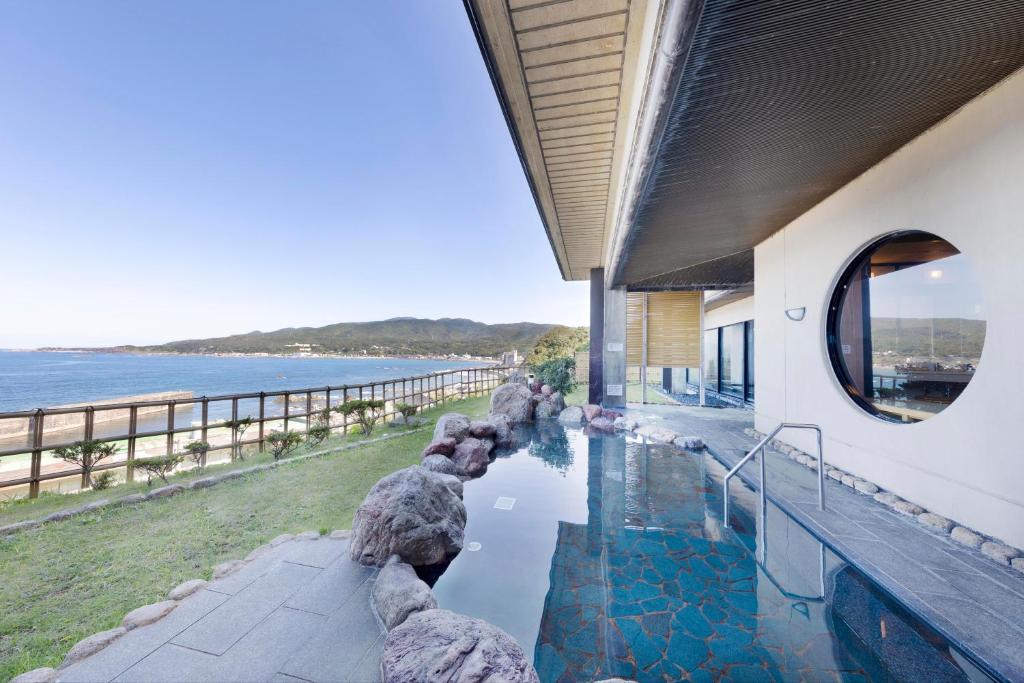 une maison avec une piscine à côté de l'océan dans l'établissement Hotel Oosado, à Sado