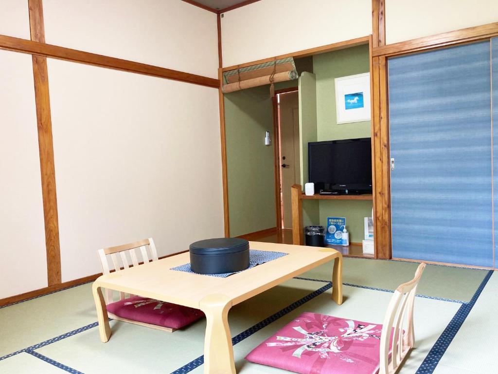 une pièce avec une table, des chaises et une télévision dans l'établissement Shinyu Onsen Kurikomaso, à Kurihara