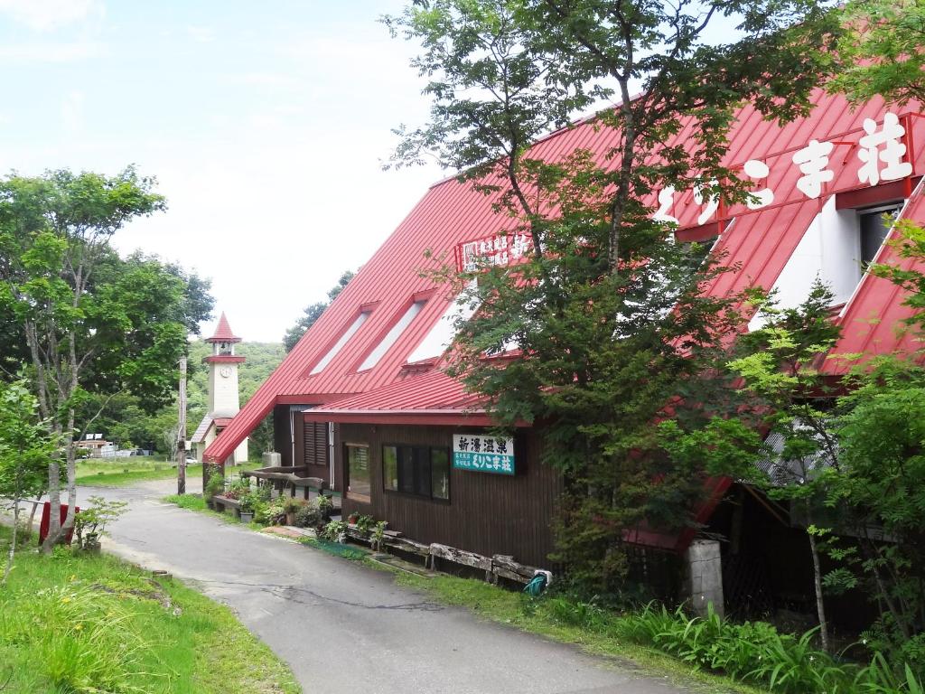 un bâtiment avec un toit rouge à côté d'une route dans l'établissement Shinyu Onsen Kurikomaso, à Kurihara
