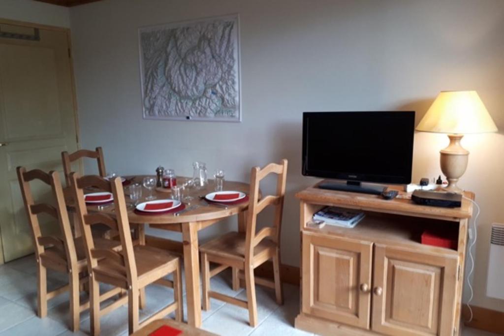 une salle à manger avec une table avec des chaises et une télévision dans l'établissement Le Chalet de Montalbert 25C, à Montalbert
