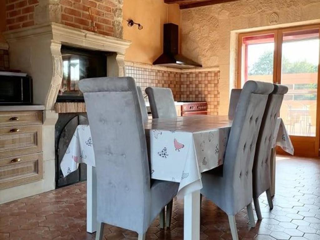 une cuisine avec une table et des chaises dans une pièce dans l'établissement Gîte en campagne rénové avec cheminée, grands jardins, WiFi, près d'un village médiéval. - FR-1-410-334, à Moitron-sur-Sarthe