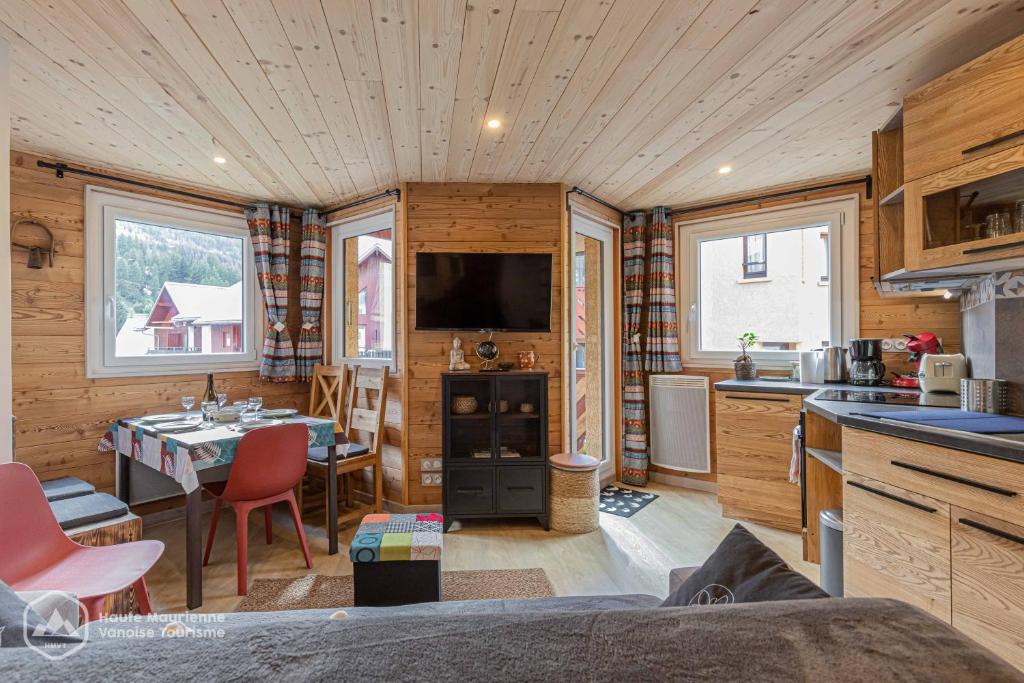 une cuisine et un salon dans une cabane en rondins dans l'établissement Roc de Burel, à Lanslevillard