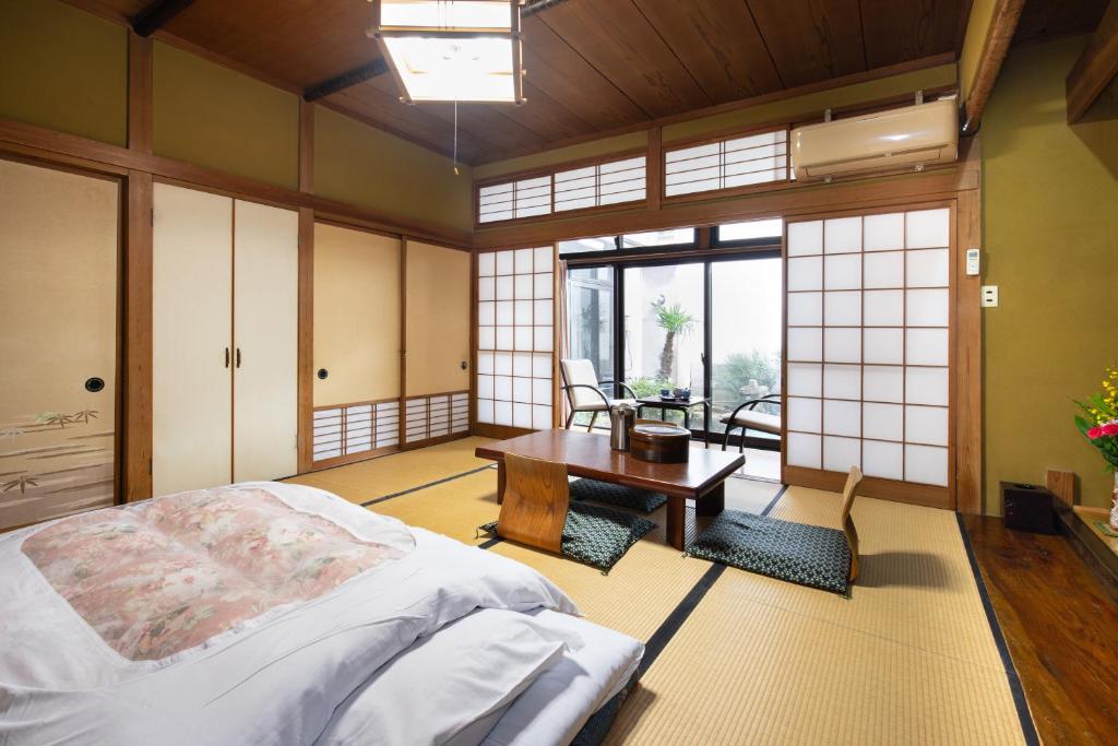 une chambre avec un lit, un bureau et une table dans l'établissement Daibutsu Ryokan, à Takaoka