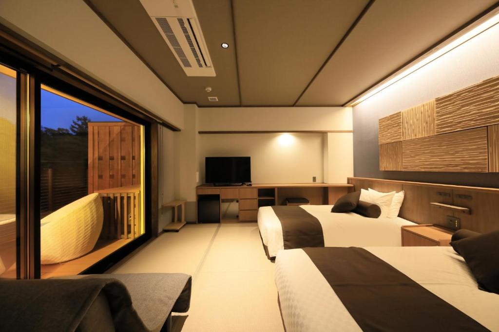 une chambre d'hôtel avec deux lits et une grande fenêtre dans l'établissement KusatsuOnsen AeruyadoTakamatsu, à Kusatsu