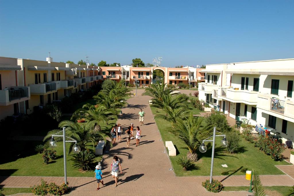 un groupe de personnes marchant dans une cour d'un bâtiment dans l'établissement Hotel Thàlas Club, à Torre dell'Orso