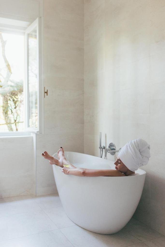 une femme allongée dans une baignoire dans une salle de bain dans l'établissement Hotel Orione - Lake Front Hotel, à Brenzone