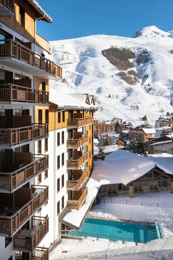 un hôtel dans la neige avec une montagne en arrière-plan dans l'établissement Résidence Club MMV Les Clarines, à Les Deux Alpes