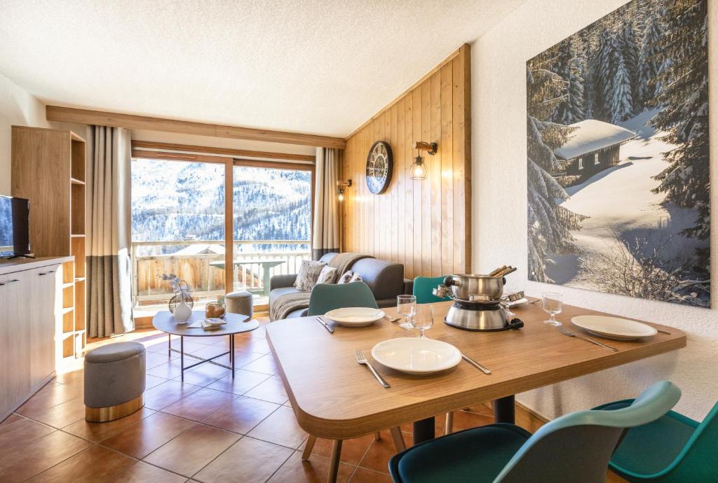 une salle à manger avec une table et des chaises et une cuisine dans l'établissement Résidence Club mmv Le Hameau des Airelles ****, à Montgenèvre