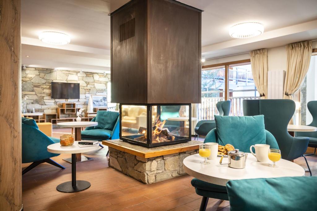 - un hall avec une cheminée, des tables et des chaises dans l'établissement Résidence Club mmv Le Hameau des Airelles ****, à Montgenèvre