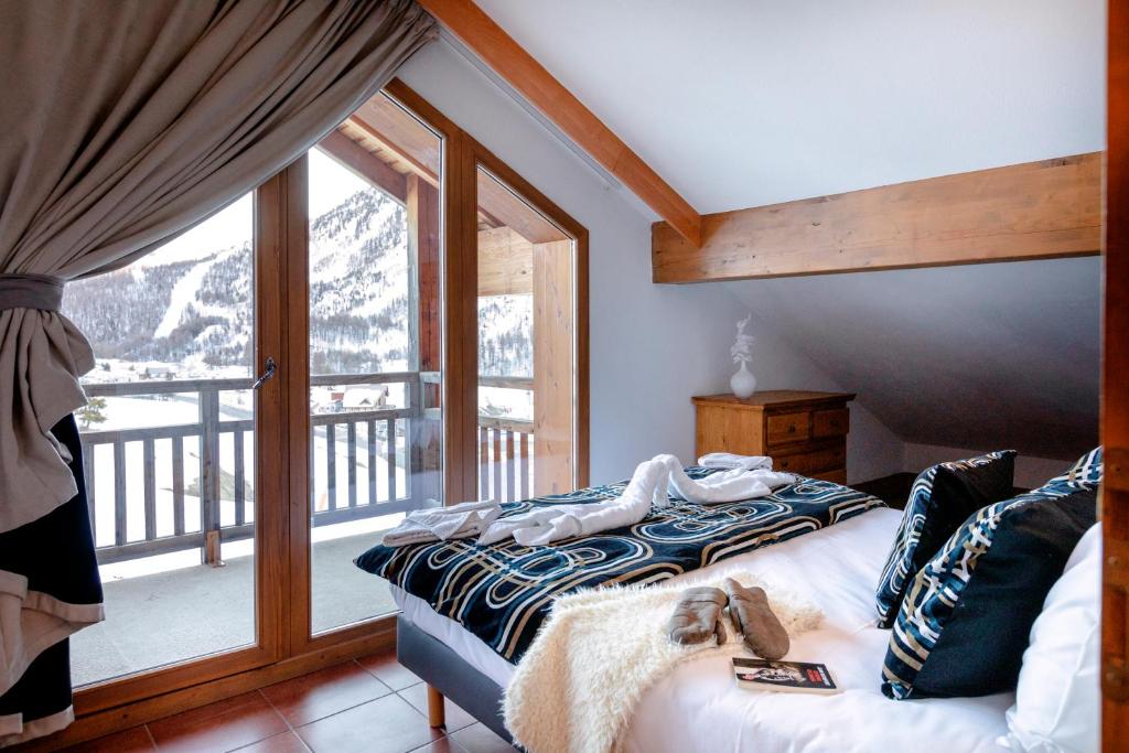 une chambre avec un lit et une grande fenêtre dans l'établissement Résidence Club mmv Le Hameau des Airelles ****, à Montgenèvre