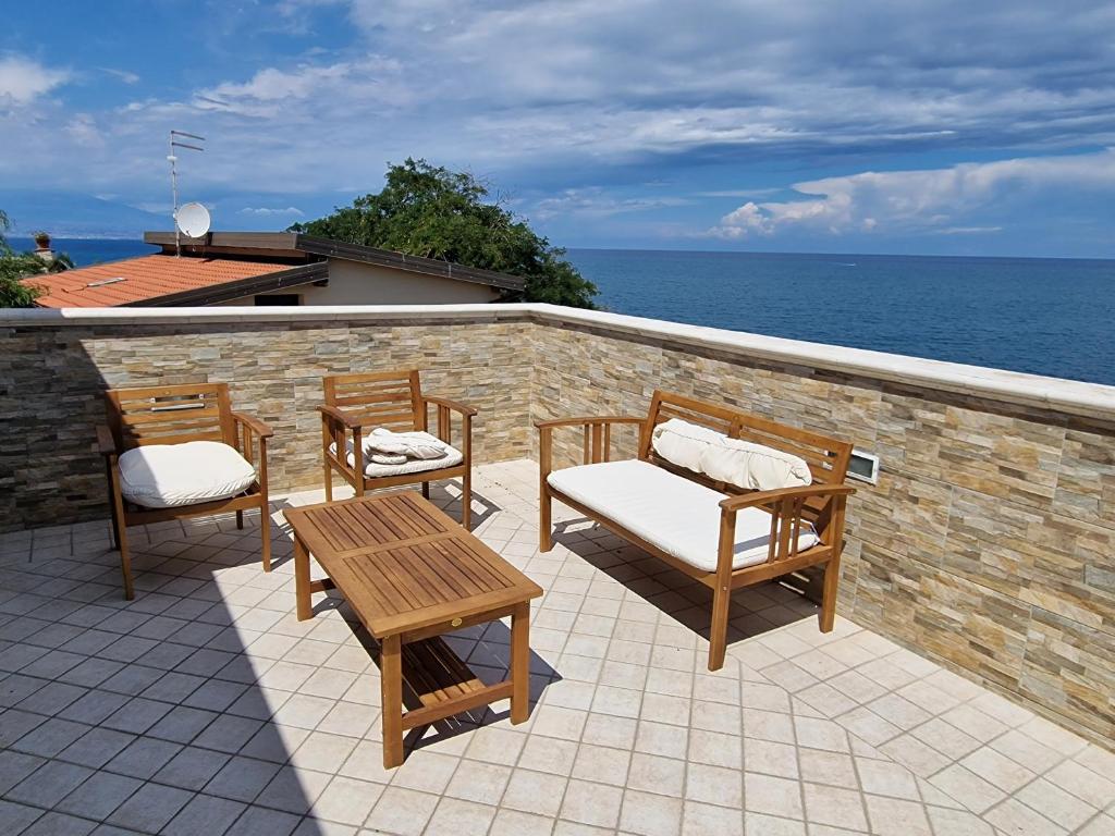 d'une terrasse avec 2 chaises et une table et des chaises en bois. dans l'établissement Villa Daniela - Villa con piscina privata e discesa a mare tra Catania e Siracusa, à Augusta