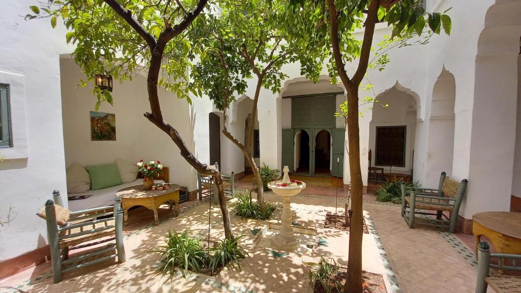 une cour avec des arbres, un canapé et des tables dans l'établissement Dar El Kharaz, à Marrakech