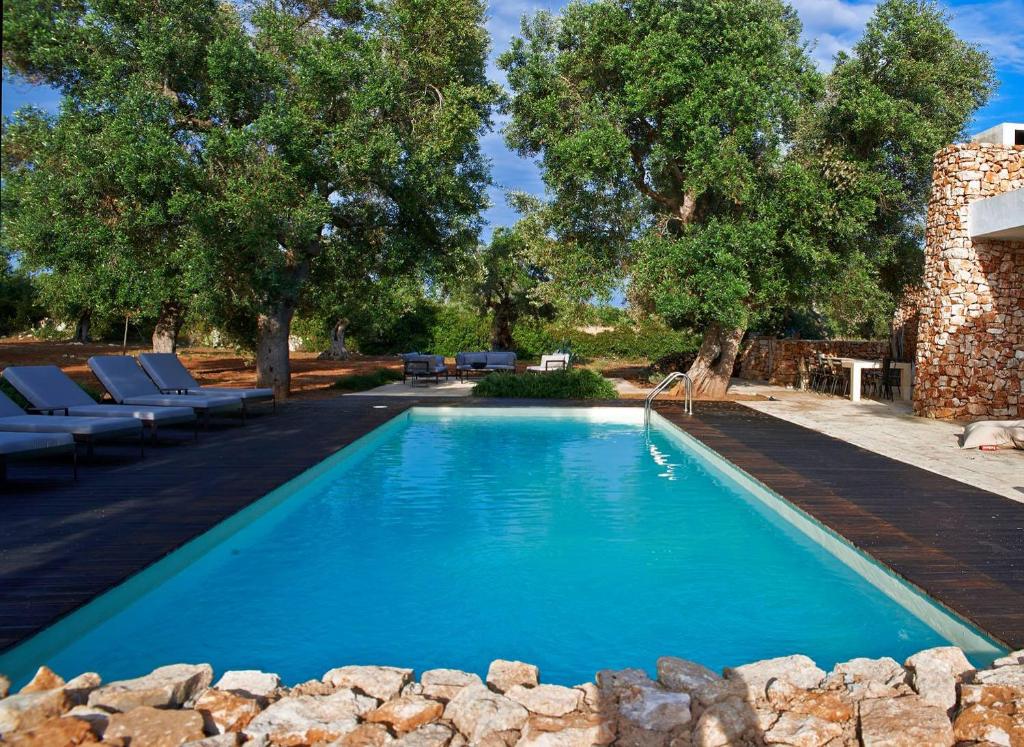une piscine avec de l'eau bleue dans une cour dans l'établissement Bosco degli Ulivi, à Morciano di Leuca