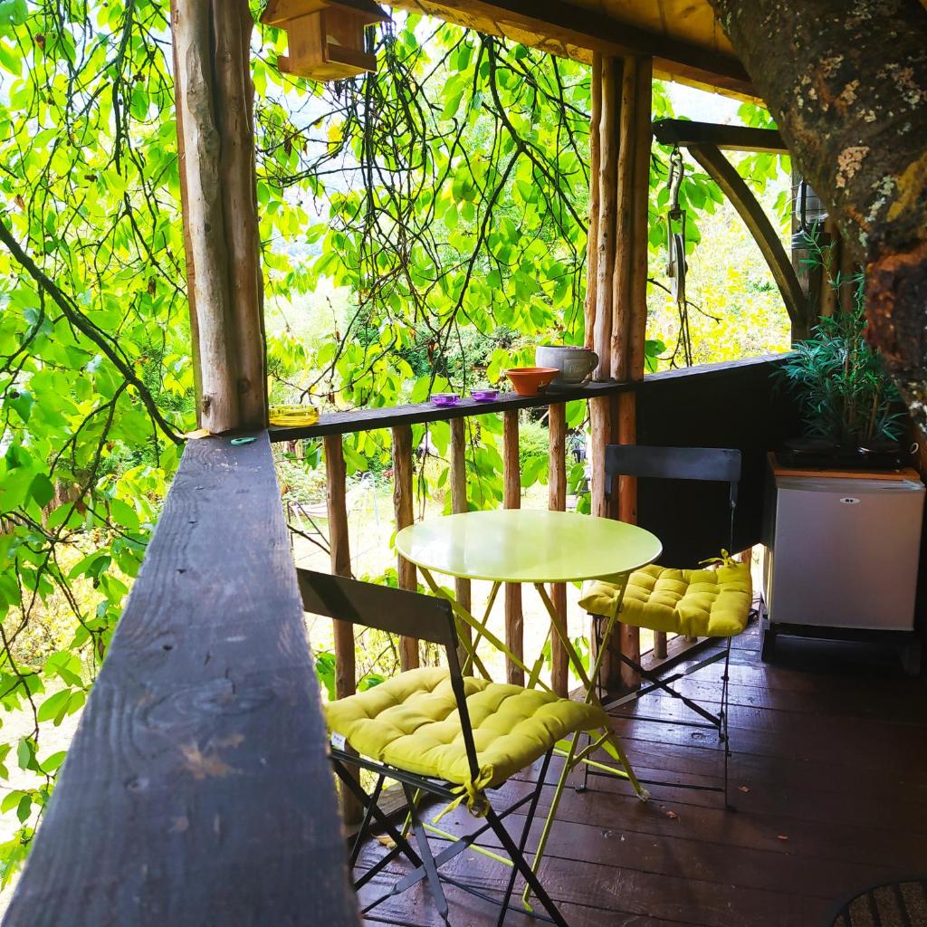 un patio avec une table et des chaises sur un porche dans l'établissement CABANE CERISE DANS L'ARBRE Etapeboisee, à Fumay