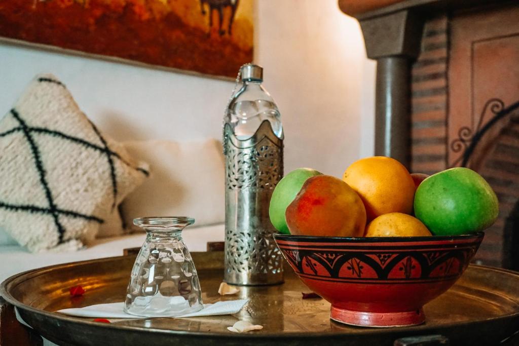 - un bol de fruits sur une table avec une bouteille dans l'établissement Riad Nora, à Marrakech